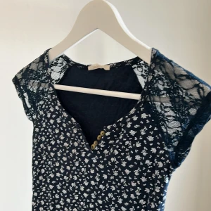 Topp - T-shirt med spetsarmar och blommönster. Köpt i Italien 