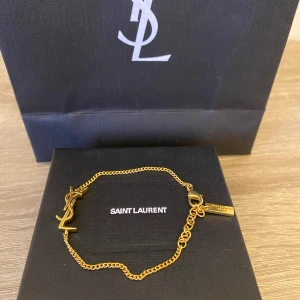 Yves Saint Laurent armband  - Säljer detta snygga armband från YSL som är perfekt till sommaren. Fick det i present och kommer inte till användning. 9/10 skick inga deffekter alls. Box och påse tillkommer. Nypris ca 3500, mitt pris 1199. Bara skriva vid frågor. 