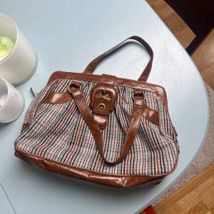 En brun handväska med fint mönster, dragkedja och spänne med fack på insidan 😊