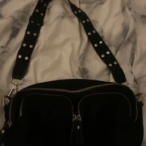 Noella väska  - Svart silver väska som inte kommer till användning, inga skador på väskan. Ni får med en extra band på köpet. 💕