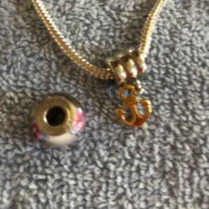 Silver armband  - Ett silverarmband m två berlocker.  En berlock är i silver 925, m rosa & vita detaljer.  De är oanvända. Längden är 17 cm. 