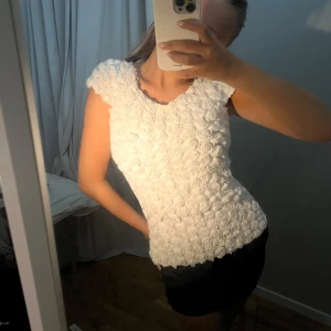 TOPP MED VITA ROSOR - Säljer en superfin vit topp från Orsay. Den har ett unikt mönster med rosdetaljer över hela framsidan, denna är köpt för 500kr och säljs mycket billigare! 🩷 Tryck köp nu för tidig leverans