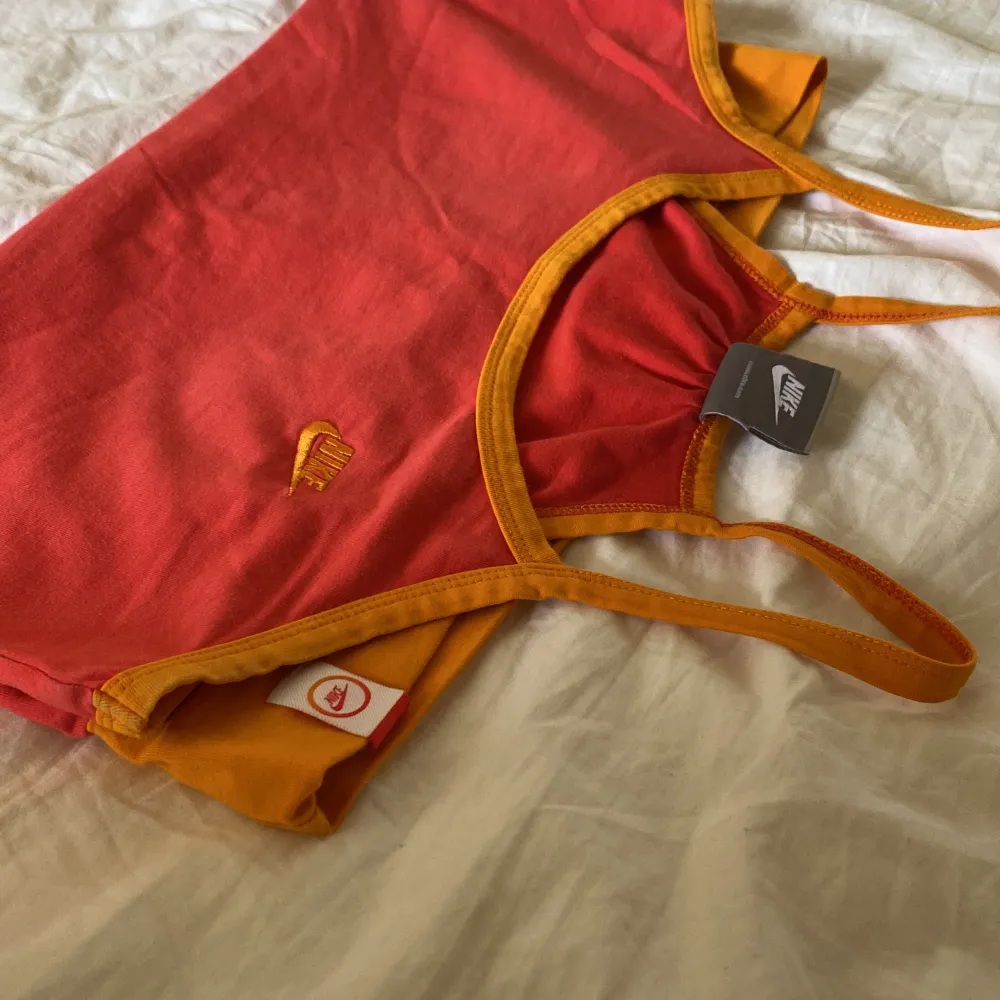 Vintage corall rött Nike linne med orange detaljer, köpt här på Plick. Säljer då det tyvärr ej kommer till användning. Färgen syns bäst på sista bilden💛. Yläosat.