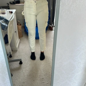 Vita cargopants i jeansmaterial - Säljer ett par vita cargopants i jeansmaterial. Byxorna har flera fickor på sidorna och en bekväm passform. Perfekta för en avslappnad och stilren look. De är i storlek S/M stor i storleken och passar bra till både vardag och fest.