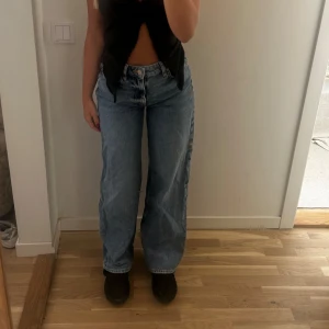 Blå jeansbyxor - Säljer ett par snygga blå jeans ifrån HM. De är högmidjade och har en loose passform. Perfekta för en avslappnad och trendig look. Byxorna har en klassisk femficksdesign och stängs med knappar och dragkedja. De är i bra skick och passar perfekt till både vardag och fest.