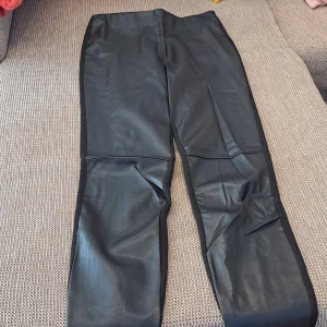 Svarta skinnleggings med slits - Säljer ett par svarta skinnleggings med slits vid anklarna. De är högmidjade och har en tight passform. Perfekta för en cool och edgy look! 🖤 oanvänd. 