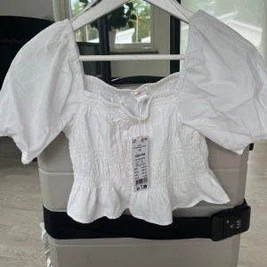 Vit blus  - Oanvänd vit blus i kort modell i storlek: 158-164 från Gina Tricot.