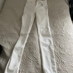 Vita jeans från Great Basics - Säljer ett par snygga vita jeans från Lager 157 i storlek S. De är helt nya med taggar kvar. Jeansen har en dragkedja och knapp framtill, samt fem fickor. Perfekta för både vardag och fest!