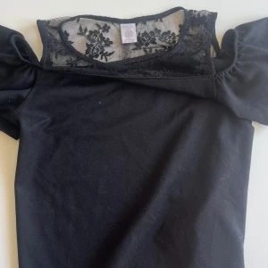 Svart spets topp med volang - Hej, jag säljer en jättefin topp från Lindex med både spets och volang detaljer på. Toppen är slutsåld och använd ett fåtal gånger och är i fint skick. Storleksmässigt skulle säga att toppen är i S/M😇☺️passar perfekt till flera olika tillfällen! 