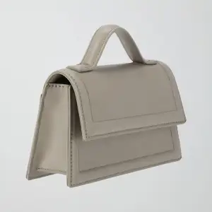 Säljer denna grå/beiga mini crossbody-väska från Gina Tricot. Aldrig använd. Pris: 150 kr (nypris: 299 kr).