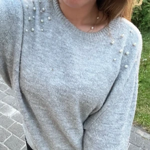 Grå stickad tröja med vita pärlor  - Jag säljer en grå stickad tröja från H&M med vita pärlor på🤍Jättesöt tröja i bra kvalitet. Den är mindre i storleken, skulle säga att den liknar mer S storleksmässigt 🥰