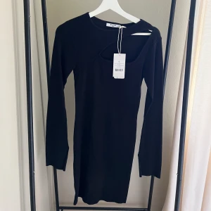 Klänning svart - En kort svart klänning med en utskiftning på framsidan. Klänningen har slits i armarna. Perfekt till fest.  Endast provad  