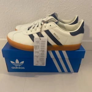 Nya retro Adidas Gazelle - Adidas originals gazelle j i storlek 36 2/3 och även i 37 1/3. Färgen är krämvit och mörkblå (Off White-Dark Blue-Gum 2) Nya och oanvända med tags.  Unik modell med vintage inspiration. Indoor Handball Spezial Samba