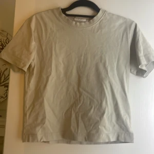 T-Shirt  - En beige t-Shirt tröjan är tjockt i materielet