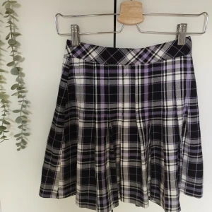 Pleated Kjol  - En söt lila/svart/vit pleated kjol för barn och tonåringar. Storlek: 146/152 10-12Y. Kan justeras i midjan. Finns knapp och dragkedja. Köpt i Lindex. Skön material och använd ett fåtal gånger, som i nyskick.