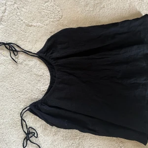 Svart top - Svart topp med rosetter. Från HM storlek M