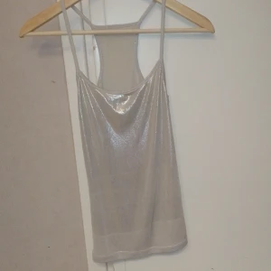 Silverblänkande linne Strl S   - Superfint glittrande/blänkande silvrigt linne, blankt tyg. Tight modell. Perfekt för nyår 😍 Strl S men funkar även för XS. Mycket bra skick!