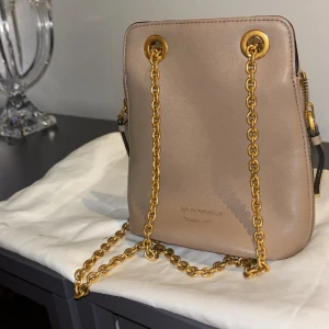 Armani väska  - En fin väska i beige brun ljus färg som inte har används ofta. En fin liten väska som går att använda till fester eller i vardagen och har en bra utrymm för mobil och mkt annat. Det är gulddetaljer som är väldigt fint. Jag köpte den för 1500kr. Äkta väska