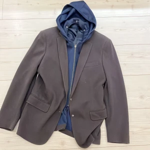 Modern kavaj  - Snygg kavaj med integrerad innertröja/hätta från Sean John. Köpt i usa.  Hättan är avtagbara med knappar på insidan. Hittar ingen storlek men passar en genomsnittlig medium. 