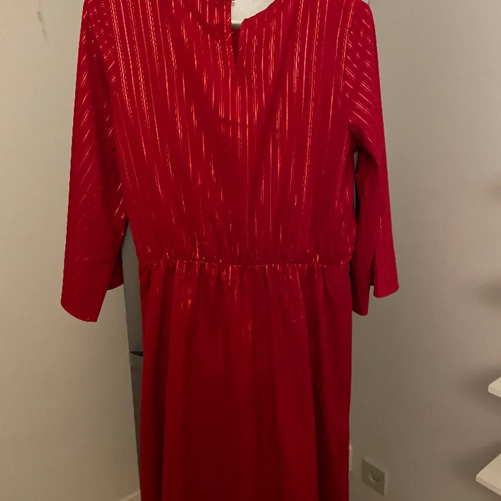Röd klänning med resår i midjan för skurningen. Omlott klänning med en dekorknut på sidan.  Från Lindex i storlek 170. Klänningar.