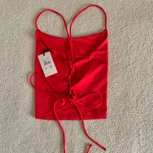 BikBok rött linne med snörningar i ryggen - Jättefint linne från BikBok med korsade snörningar i ryggen. Aldrig använd, nytt med tags kvar.