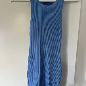 Stickad klänning - Blå klänning som följer kroppen, hög i halsen och ribbad i tyget