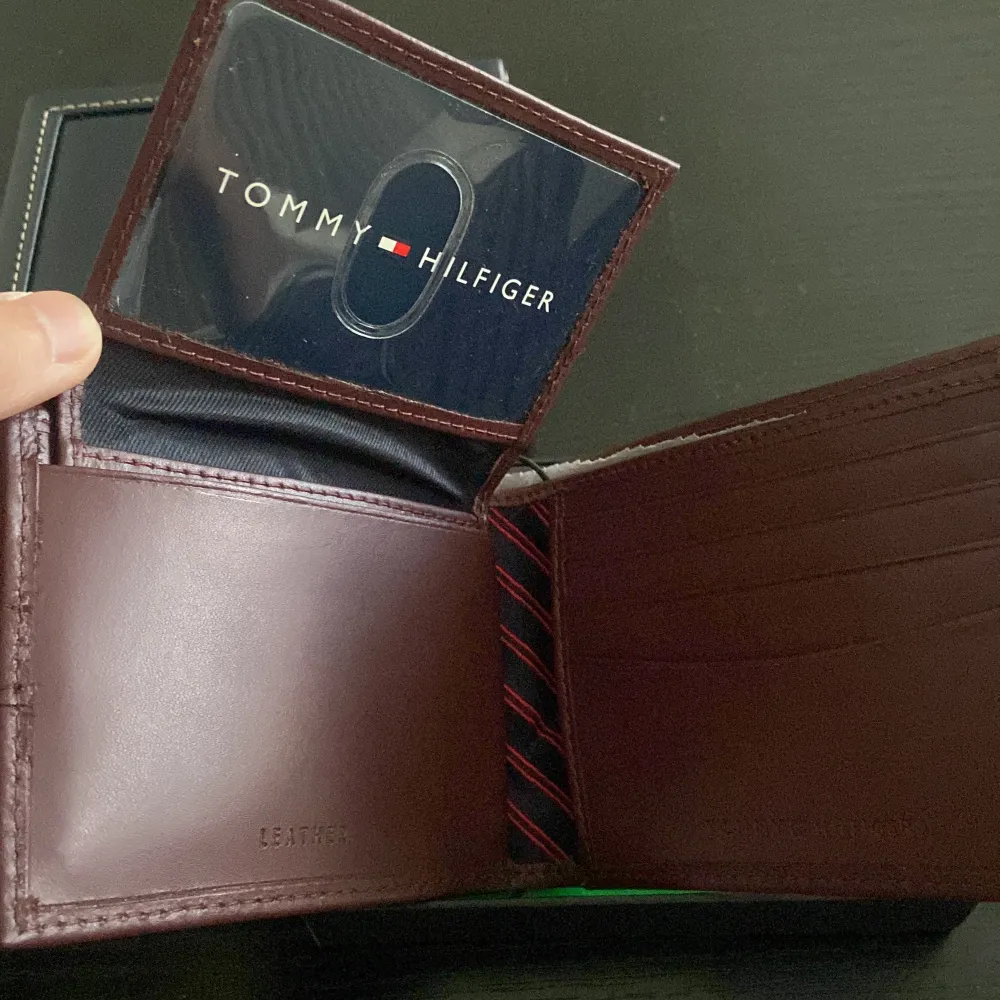 Tommy hilfiger plånbok som aldrig använts. Helt oanvänd i burgundy färg. Kommer med låda. . Övrigt.