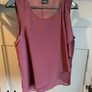 Topp i vinröd - Topp i vinrött med volang på vänster sida. Ger en fin detalj. 