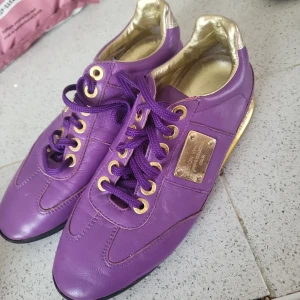 Snygga fotbollsskor i lila med guld detaljer - Använda vid några tillfällen. Köpta för 110kr i butik.