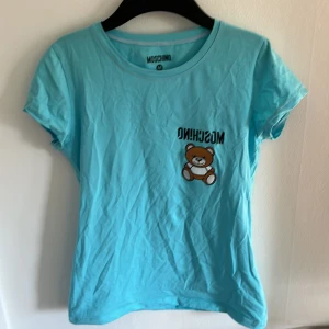 T-shirt av märket moschino - En turkos tröja köpt från Moschino i storlek M med passar också S. Användt den få gånger så den är som ny.