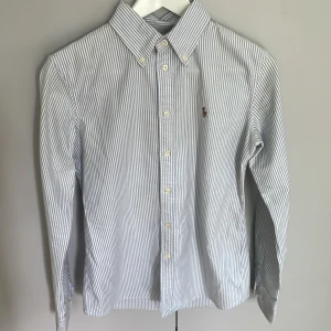 Ralp Lauren skjorta - Fin blå och vit randig skjorta ifrån Ralph lauren, mycket sparsamt använd därav jättebra skick. Säljes endast då den inte kommer till användning. Köparen står för frakten!