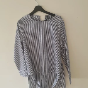 Skjorta - Den är utsvängd vid armarna och kort vid framsidan