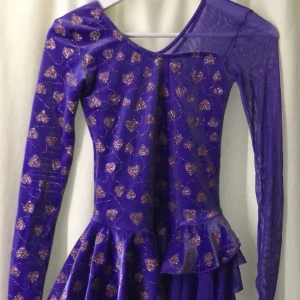 Lila klänning från Mondor - En lila klänning från Mondor med glittriga hjärtan. Klänningen har långa ärmar och en volangdetalj vid midjan.