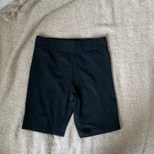 Svarta ribbade shorts från 157 New - Ett par svarta ribbade cykelbyxor från 157 New. Shortsen har en elastisk midja och är tillverkade i ett ribbat material.