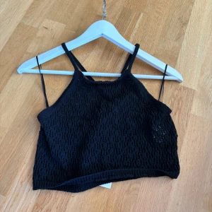 Virkad topp  - Virkad, svart topp med band korsade i ryggen. Har aldrig använts och lappen är kvar.