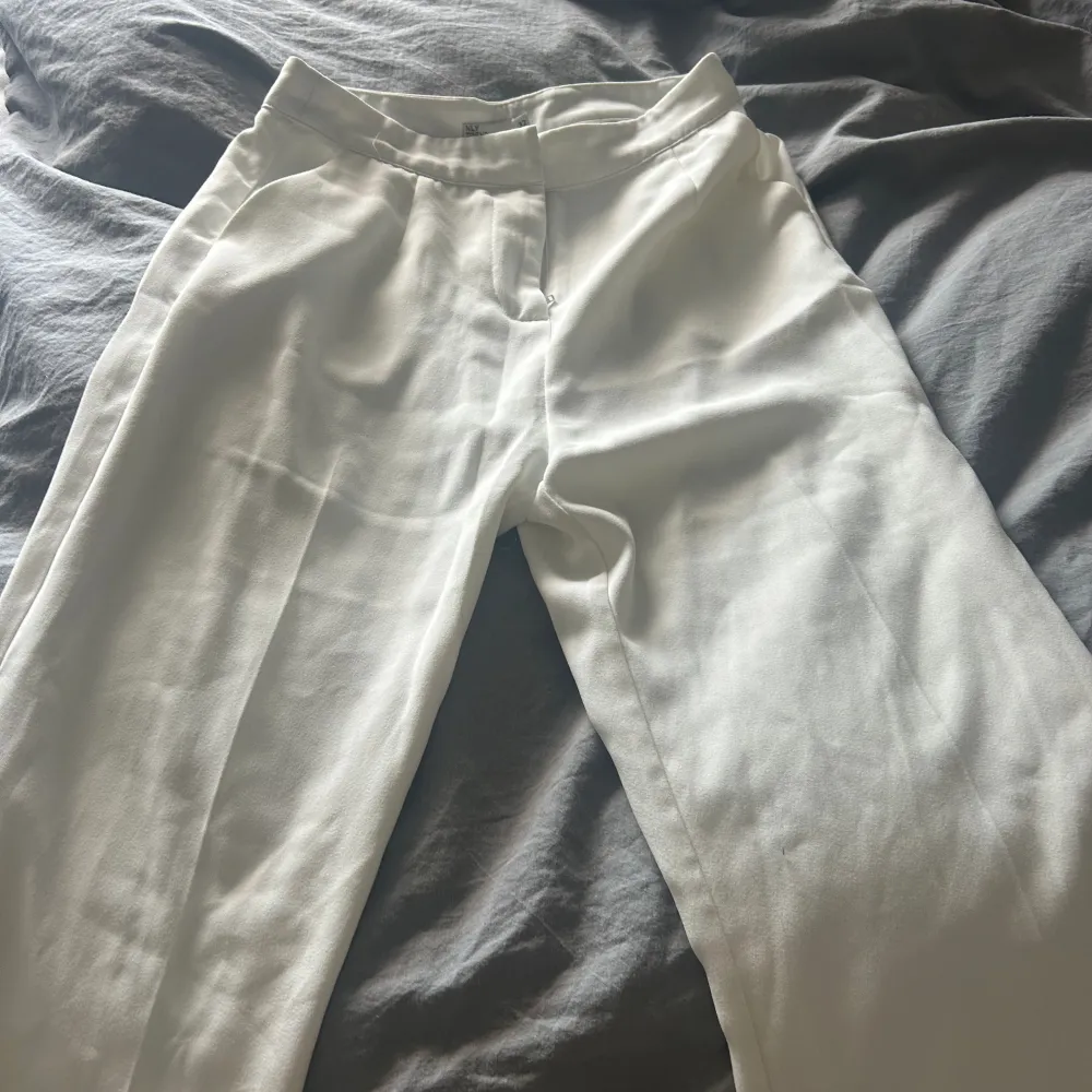 Fina vita kostymbyxor från Nelly, aldrig använt. Köptes för 499kr och säljer för 299kr💕storlek  32 men passar 34/36 då de är långa . Jeans & Byxor.