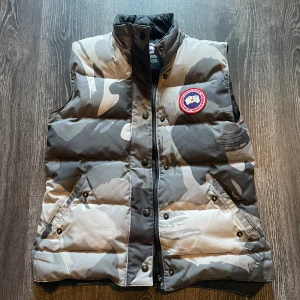 Canada Goose Väst - Säljer nu min äkta Canada goose väst storlek M/MDam men den passar även killar (använd av mig). Västen är i bra skick förutom draget på dragkedjan som lossnat, men har kvar den och det går att laga/ersätta. Skriv vid intresse eller funderingar!