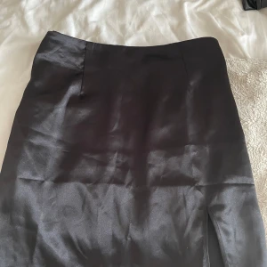 Satin kjol  - Fin satinkjol i storlek XL, säljer pga är för stor för mig, kjolen har en liten slit på vänstra sidan och har en dragkedja på sidan. Kjolen är aldrig använd eftersom jag ej hann returnera. Hör av dig vid intresse!