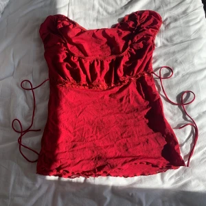 Topp - riktigt snygg röd topp med söta detaljer. spets och band i midjan. har ett snöre som kan knytas fram eller bak. materialet är typ mesh.