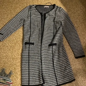 Svart kofta med vita detaljer - Svart  kofta med vita detaljer . Stickad. Fint skick. Fejk fickor. Medellång. Pris går att diskuteras. Slutsåld överallt och tillverkas ej längre. 