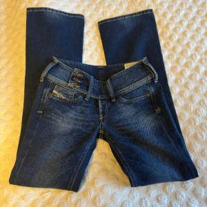 Grymt snygga jeans från Deisel i nyskick! Tyvärr för små för mig, dom är riktigt snygga och förtjänar att komma till användning. Cherock. Mörkblå. Low waist. Stretch. Flare. W27 L33. Innerbenslångd 80cm. Midja mätt rakt över va 34.