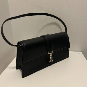 Handväska - Säljer denna svarta handväska med gulddetaljer ifrån H&M. Som ny då den endast är använd några få gånger. Pris: 150kr🩷