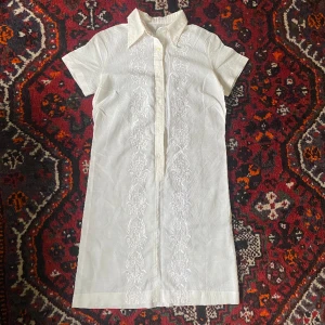 vit skjortklänning - jättefin vintage kort vit skjortklänning i country/cowboy-stil (?) med broderat mönster! fåtal små fläckar (se bild) men syns knappt, annars i bra skick!
