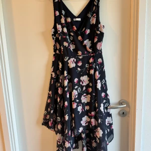 Blommig klänning med omlott  - Marinblå klänning med rosa blommor. Storlek 34