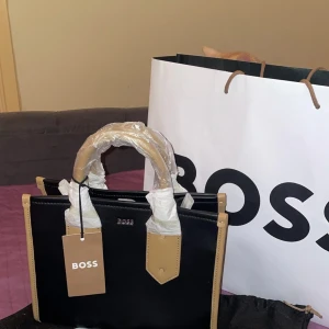 Boss Väska Dam - Min boss väska är helt ny köpte för 2000 har använt den bara 1 gång! Den är helt ny! Säljer eftersom den kommer inte till användning för mig💕 Hör av er om ni vill diskutera priset 🥰
