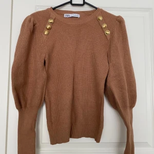 Jättefin tröja från Zara - Jättefin beige tröja från Zara med guldiga knappar.  Tröjan är i fint skick, använd Max 2-3 gånger.  Tröjan är I storlek L men liten i storleken så skulle säga den är som M.