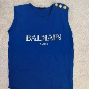 Balmain topp-T-shirt  - Väldigt fin Balmain topp. Har endast användt den 1-2 ggr. Har bara legat i garderoben. Väldigt fin och fräsch. Normal i storlek.