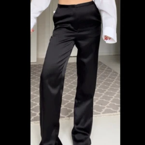 Glansiga kostymbyxor - Svarta högmidjade kostymbyxor i satin-imitation från H&M säljes då de är för långa🖤