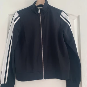 Tröja med dragkedja - Svart tröja med dragkedja och vita sträck på armarna