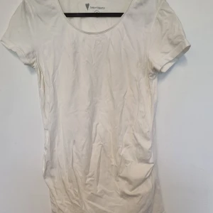 Vit gravidt-shirt strl. S (36/38) - Vit gravid-t-shirt i storlek S (36/38) från Heartbeats. Stretchig och därmed rymlig. I fint skick, inga hål eller fläckar.   Tvättad i parfymfritt tvättmedel och utan sköljmedel. 